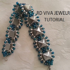 May include: A silver and blue beaded bracelet with a geometric design. The bracelet is made with small seed beads and larger, faceted beads. The text "RD VIVA JEWELRY TUTORIAL" is visible in the image.