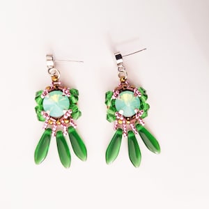 Könnte beinhalten: Ein Paar handgefertigte Ohrringe mit einem zentralen hellblauen Kristall, umgeben von grünen und rosa Perlen. Die Ohrringe haben drei grüne, tropfenförmige Anhänger. Die Stifte sind silberfarben.