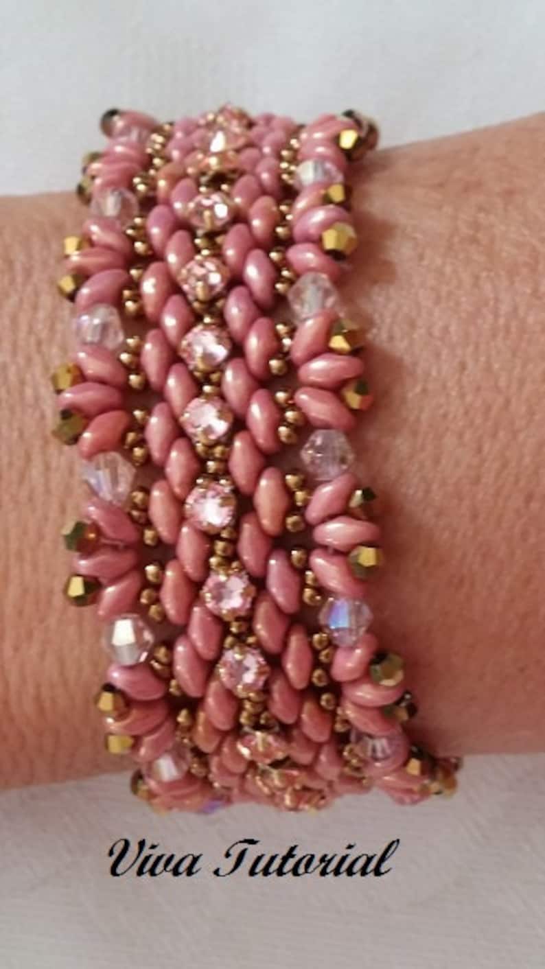 Puede incluir: Un brazalete de cuentas rosa y dorado con un patr&oacute;n tejido. El brazalete est&aacute; hecho con peque&ntilde;as cuentas rosas y cuentas doradas, y presenta detalles de cristal transparente.
