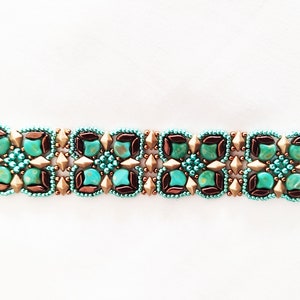 Op de afbeelding: Een turquoise, bruin en gouden kralenarmband met een geometrisch patroon.