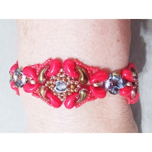 May include: A red beaded bracelet with gold and clear accents. The bracelet features a central design of red, gold, and clear beads.