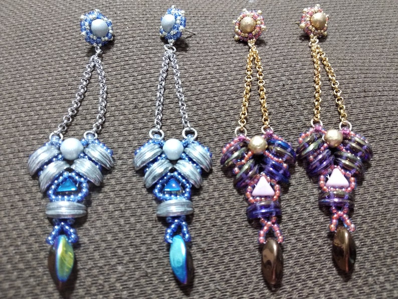 May include: Four pairs of beaded dangle earrings. Two pairs feature silver-toned chains and blue and silver beads. The other two pairs have gold-toned chains and purple, pink, and brown beads. Each earring has a unique design.