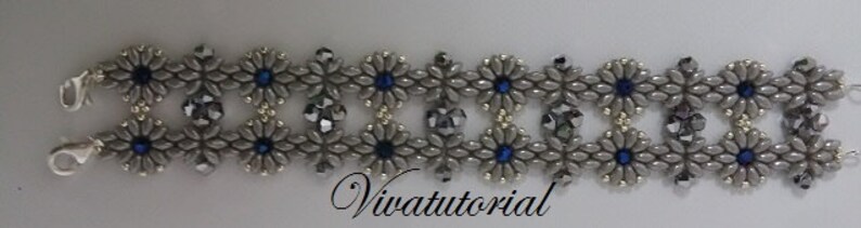 May include: A silver and blue beaded bracelet with a floral design. The bracelet is made with small seed beads and features a repeating pattern of silver and blue beads.