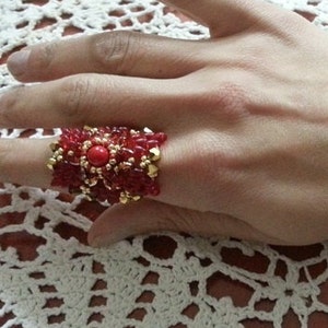 May include: A red and gold beaded ring with a large red gemstone in the center.