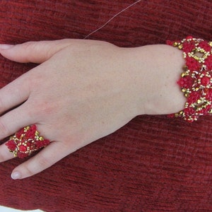 May include: A red and gold beaded bracelet and ring set. The bracelet is made with small red and gold beads, and the ring is a large, ornate design with red and gold beads.