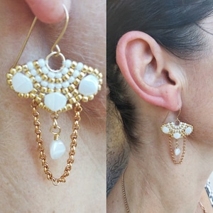May include: Gold tone earrings with white beads and a dangling chain. The earrings have a fan-shaped design with three white beads at the top.