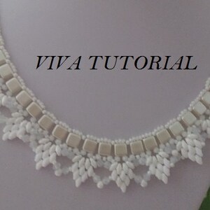 May include: A white beaded necklace with a delicate, lacy design. The necklace features a row of larger, square beads and a fringe of smaller beads. The text "VIVA TUTORIAL" is visible in the image.