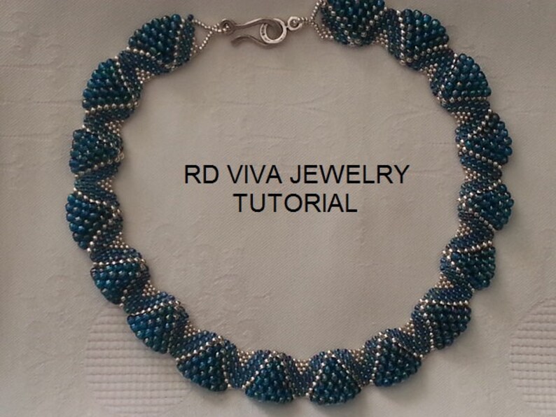 K&ouml;nnte beinhalten: Eine handgefertigte Halskette mit teal- und silberfarbenen Perlen. Die Halskette besteht aus mehreren Perlenabschnitten, die durch silberfarbenes Metall verbunden sind. Der Text "RD VIVA JEWELRY TUTORIAL" ist auf dem Bild zu sehen.
