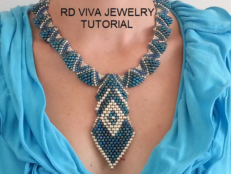 K&ouml;nnte beinhalten: Eine Perlenkette mit einem geometrischen Anh&auml;nger. Die Halskette hat blaue und silberne Perlen in einem Spiralmuster mit einem rautenf&ouml;rmigen Anh&auml;nger. Der Text "RD VIVA JEWELRY TUTORIAL" ist oben im Bild zu sehen. Die Halskette wird vor blauem Hintergrund getragen.