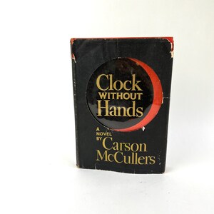 May include: A black book with a red and gold title that reads "Clock Without Hands" by Carson McCullers.