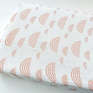 May include: White fabric with a repeating pattern of rust-colored half-circle designs. The fabric is folded, showing the pattern across the surface. The material appears to be lightweight and suitable for various craft projects.