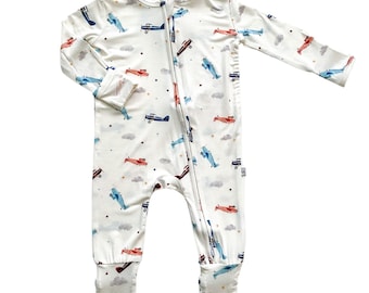 May include: White long-sleeved zippered pajamas with a print of red, blue, and white airplanes on a white background.