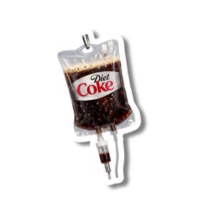 Op de afbeelding: Een doorzichtige plastic IV-zak gevuld met een donkerbruine vloeistof, die op frisdrank lijkt, met de woorden "Diet Coke" in rood en wit. De zak heeft een metalen haak en slangen.
