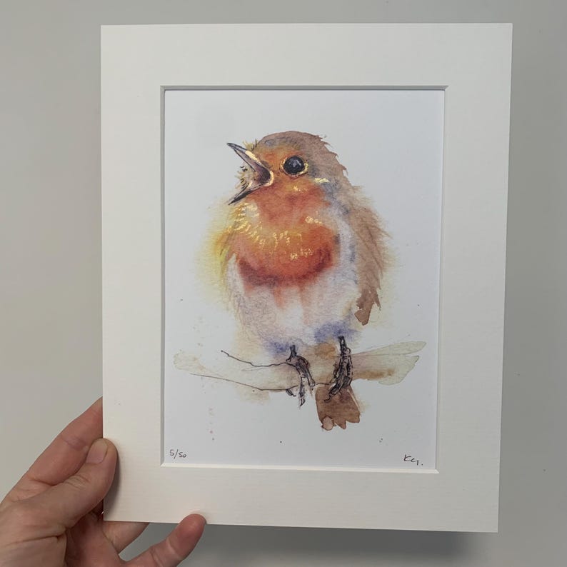 May include: A watercolour painting of a robin perched on a branch, singing with its beak open. The bird is painted in shades of brown, orange, and white, with a hint of blue on its tail feathers. The painting is signed "E.G." and numbered "5/50" in the bottom right corner.