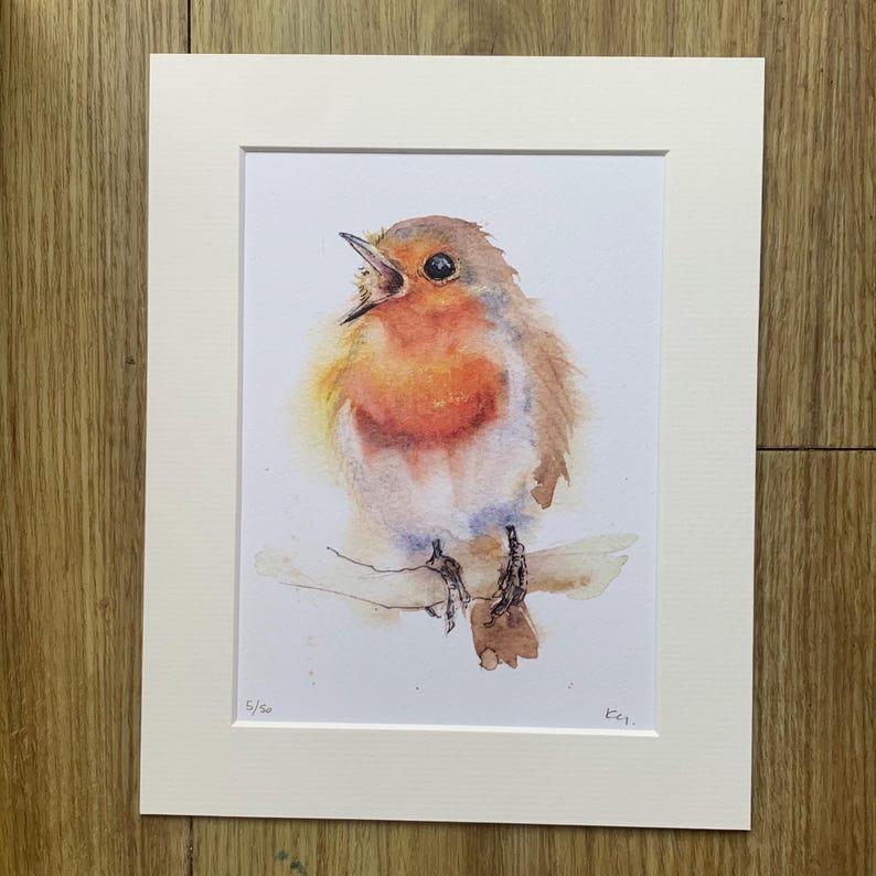 May include: A watercolour painting of a robin perched on a branch. The robin is singing with its mouth open and has a bright red breast. The painting is signed "K.G." and numbered "5/50".