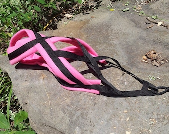 May include: Pink and black dog harness with adjustable straps. The harness is made of soft fabric and has a padded chest piece for comfort.