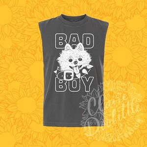 Puede incluir: Una camiseta sin mangas de color gris carbón con una ilustración gráfica blanca de un perro esponjoso con un collar de pinchos. El texto BAD BOY está impreso en letras blancas de bloque encima y debajo de la ilustración del perro.