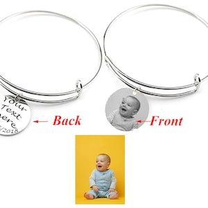 May include: A silver expandable bangle bracelet with a round charm. The charm has a personalized inscription on the back that reads "Your Text Here 02/15/2018" and a photo on the front.