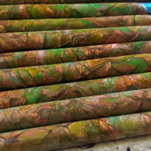 May include: Close-up of several art pencils with a marbled design. The pencils have a copper, green, and brown color scheme. The tips of the pencils are visible, with colors including blue, pink, and yellow.