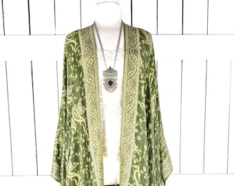May include: A long green paisley patterned kimono with a silver necklace. The kimono has a floral design and a gold trim.