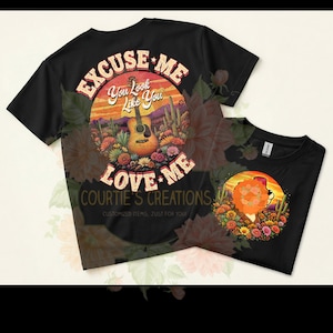 May include: Black t-shirts with a colorful graphic design. One shirt features a guitar, desert landscape, and text that reads "EXCUSE ME, LOVE ME". The other shirt has a lion design with flowers.