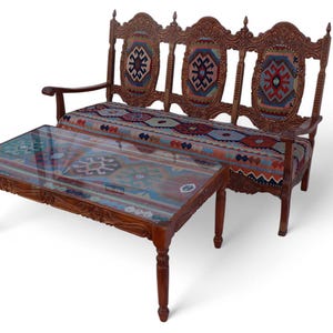 May include: A wooden sofa with intricate carvings and a colorful patterned fabric upholstery. A matching coffee table with a glass top sits in front of the sofa.