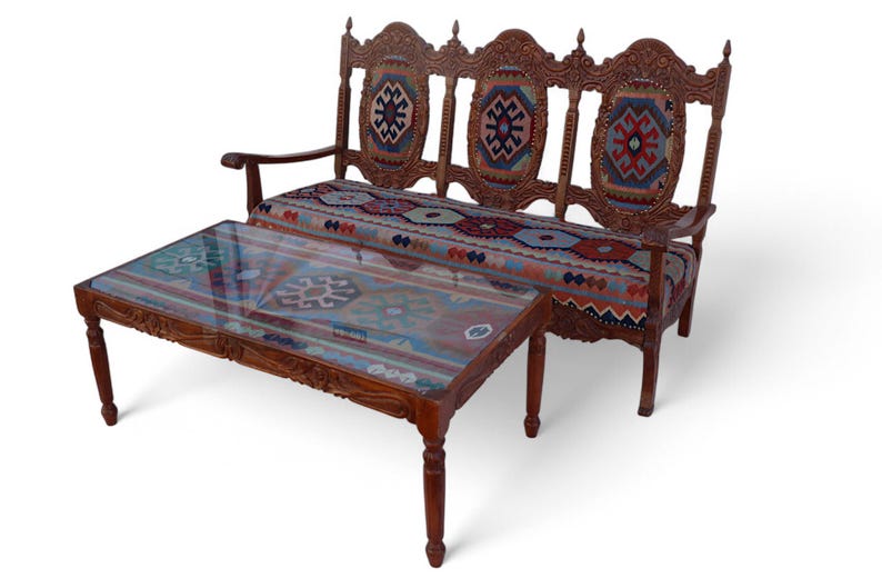 May include: A wooden sofa with intricate carvings and a colorful patterned fabric upholstery. A matching coffee table with a glass top sits in front of the sofa.