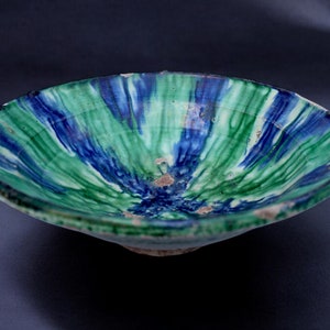 Può includere: Una ciotola in ceramica verde e blu con un motivo a spirale. La ciotola è smaltata e ha un bordo leggermente rialzato.