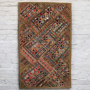 Puede incluir: Un tapiz de pared de patchwork colorido con bordados intrincados y detalles de espejo. La tela es una mezcla de marrón, rojo, naranja y verde, con un borde dorado.