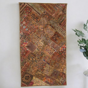 May include: A tapestry wall hanging with a patchwork design of various shades of brown, red, and blue. The tapestry is made of fabric scraps sewn together in a geometric pattern.