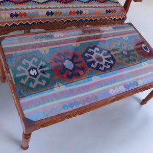May include: A wooden coffee table with a glass top and a colorful patterned rug inset. The rug has a geometric design with shades of blue, red, green, and pink.