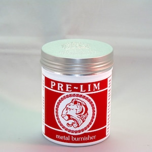 以下が含まれることがあります： 「PRE-LIM metal burnisher」と赤いラベルが付いた銀色の缶。ラベルには、赤い円の中にブルドッグの頭部のイラストが描かれている。