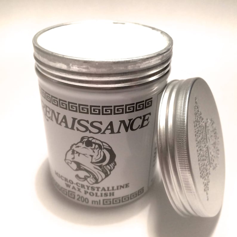 K&ouml;nnte beinhalten: Eine silberne Dose mit einem wei&szlig;en Deckel, beschriftet mit "Renaissance Micro-Crystalline Wax Polish 200 ml" und einer Schwarzwei&szlig;illustration eines Affen mit Helm.