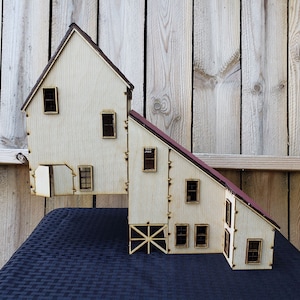 May include: A wooden model of a two-story building with a red roof. The building has multiple windows and a door. The model is made of plywood and is painted white.