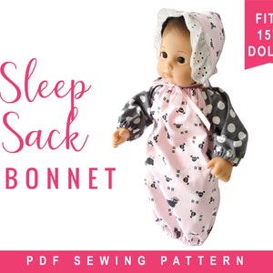 May include: A doll wearing a pink sleep sack and bonnet set with a sheep pattern. The sleep sack has gray polka dot sleeves. The bonnet has a white lace trim. Text on the image reads "Sleep Sack + Bonnet" and "Fits 15" Dolls".