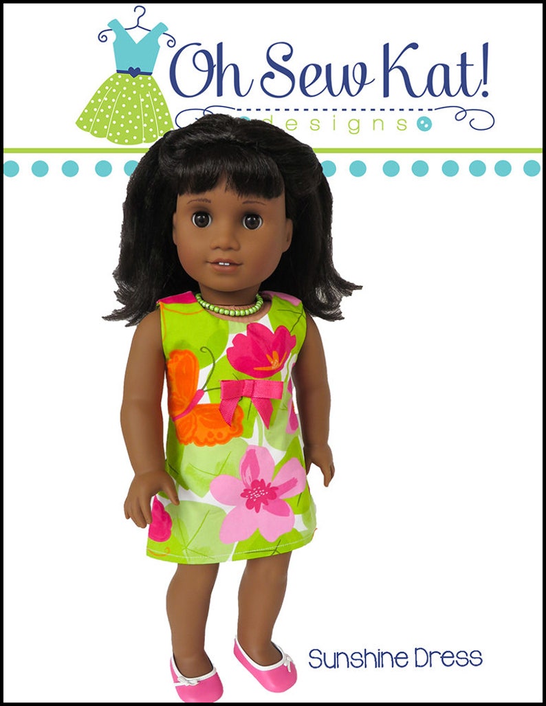May include: A doll wearing a green and pink floral dress with a pink bow. The dress is called "Sunshine Dress" and is from "Oh Sew Kat! Designs".