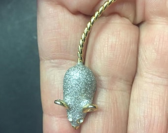 May include: A silver glitter mouse pin with a gold twisted tail.