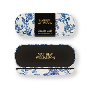 May include: A glasses case with a matching lens cloth, decorated with a blue floral design on a cream backdrop. The case is open, showing a black interior. The brand name "MATTHEW WILLIAMSON" is visible on the case and lid.