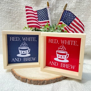 Pu&ograve; includere: Due cartelli in legno con il testo "Red, White, and Brew" e un'immagine di una tazza di caff&egrave;. I cartelli sono dipinti di rosso e blu e hanno uno sfondo bianco.