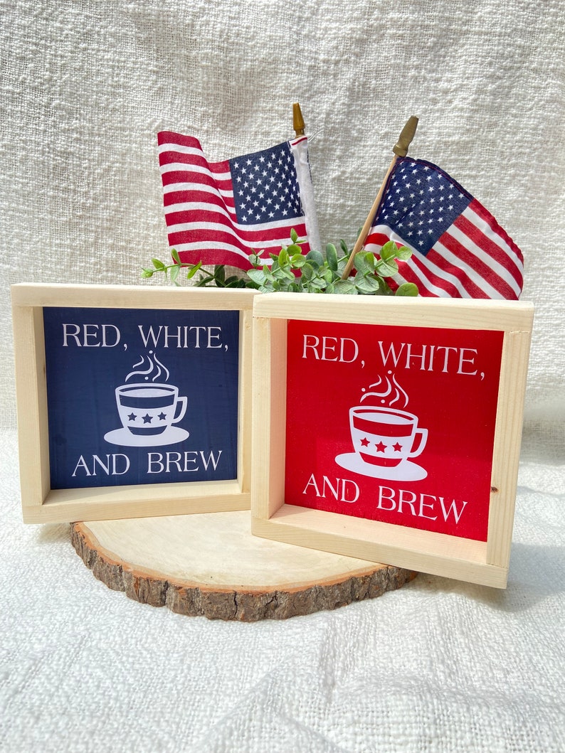 Pu&ograve; includere: Due cartelli in legno con il testo "Red, White, and Brew" e un'immagine di una tazza di caff&egrave;. I cartelli sono dipinti di rosso e blu e hanno uno sfondo bianco.