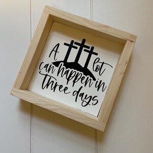 Puede incluir: Un letrero de madera blanco con texto negro y una silueta negra de tres cruces. El texto dice "Mucho puede pasar en tres d&iacute;as".