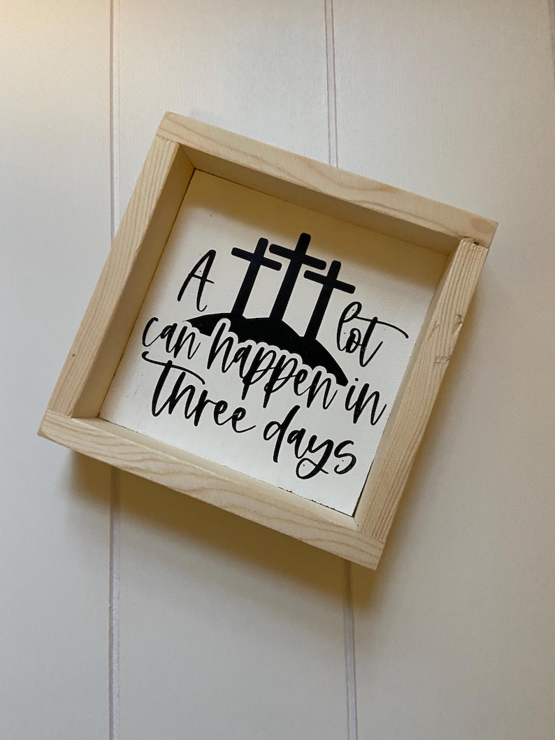 Puede incluir: Un letrero de madera blanco con texto negro y una silueta negra de tres cruces. El texto dice "Mucho puede pasar en tres d&iacute;as".
