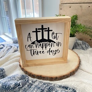 Puede incluir: Un letrero de madera con fondo blanco y letras negras. El letrero dice "Mucho puede pasar en tres d&iacute;as" y tiene tres cruces negras sobre el texto.