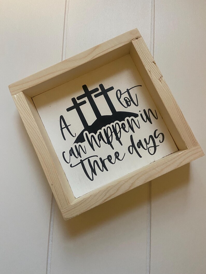 Puede incluir: Un letrero de madera con fondo blanco y letras negras. El letrero dice "Mucho puede pasar en tres d&iacute;as" con tres cruces detr&aacute;s del texto.