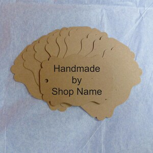 May include: A stack of brown paper gift tags with scalloped edges. The tags have a hole punched in the top and say "Handmade by Shop Name".
