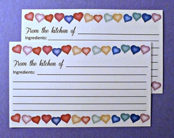 May include: Two blank recipe cards with a border of colorful hearts. The cards have lines for writing down ingredients and instructions. The text on the cards reads "From the kitchen of" and "Ingredients:"