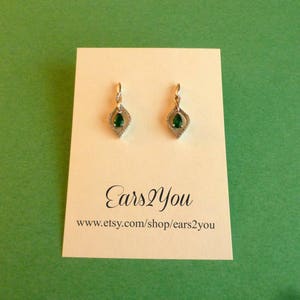 May include: A pair of gold dangle earrings with a green pear-shaped gemstone in the center of each earring. The earrings are on a white card with the text "Ears2You" and "www.etsy.com/shop/ears2you".