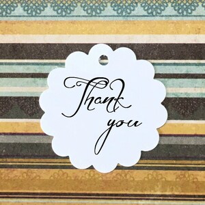 Puede incluir: Etiqueta de agradecimiento redonda blanca con borde festoneado y escritura cursiva negra.