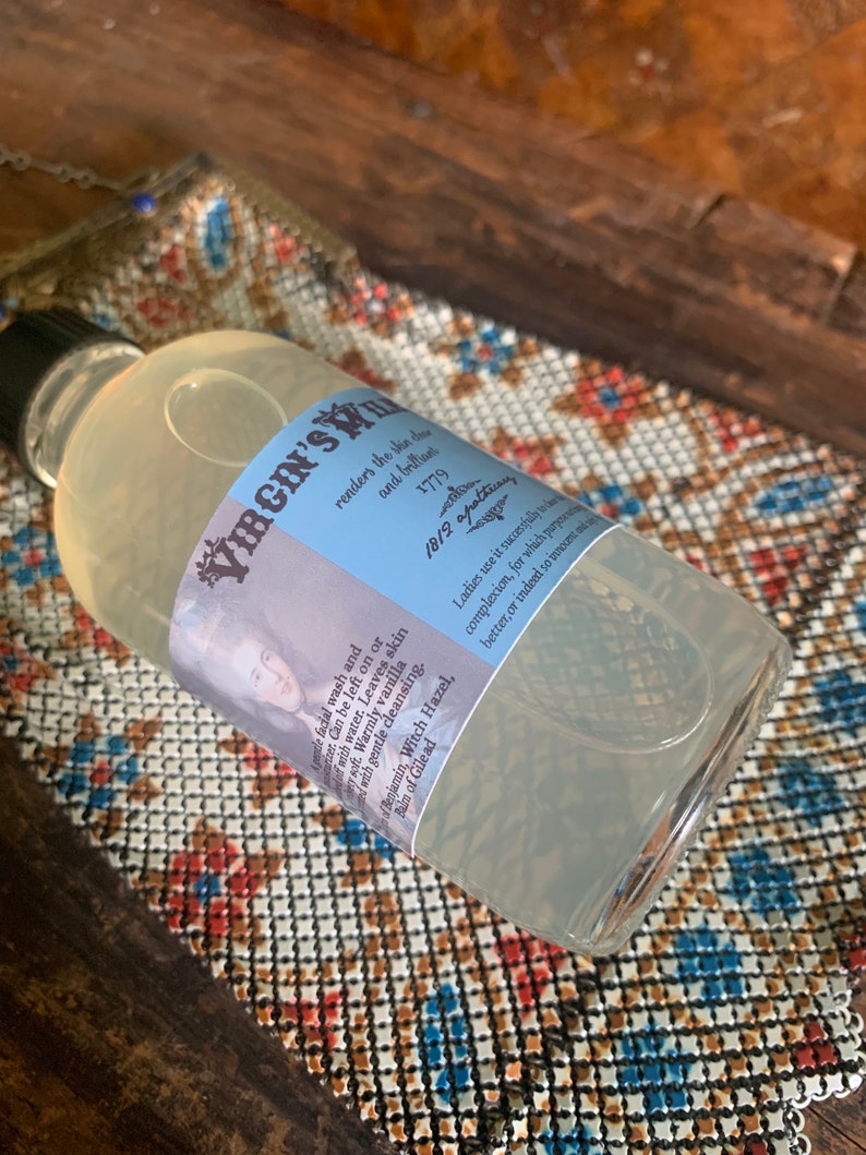 May include: A clear glass bottle with a blue and white label that reads "VIRGIN'S" and includes text about the product's use and ingredients. The bottle is sitting on a patterned surface.