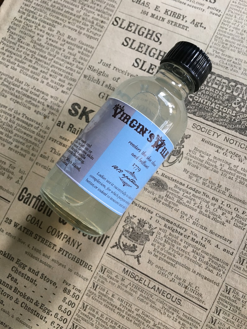 May include: A clear glass bottle with a blue label that reads "Virgin's Milk" and "renders the skin clear and brilliant". The bottle is sitting on a newspaper with text about a coal company and a lodge meeting.
